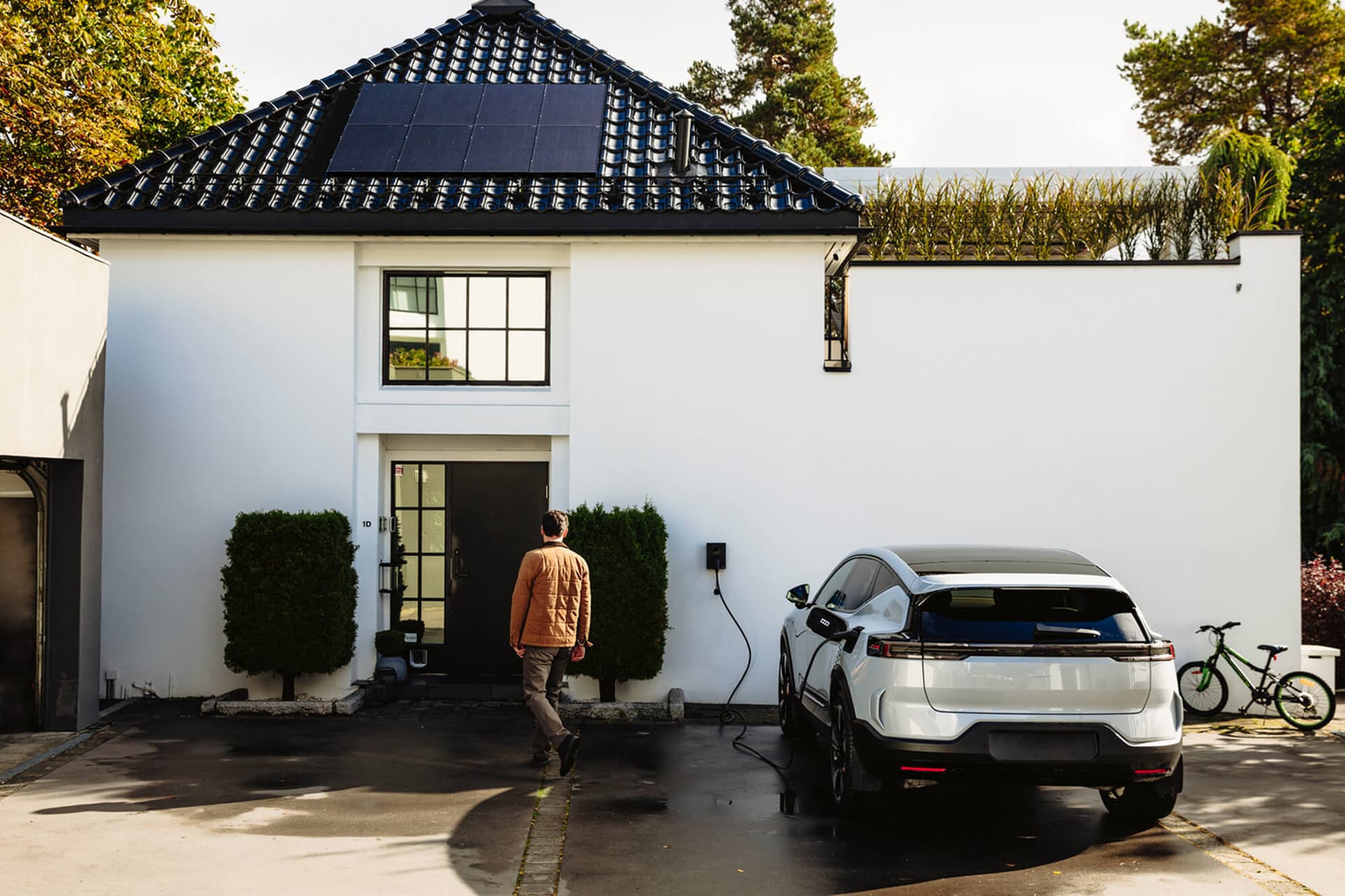 E-Auto mit Rekuperation lädt an einem Haus mit Solarstrom