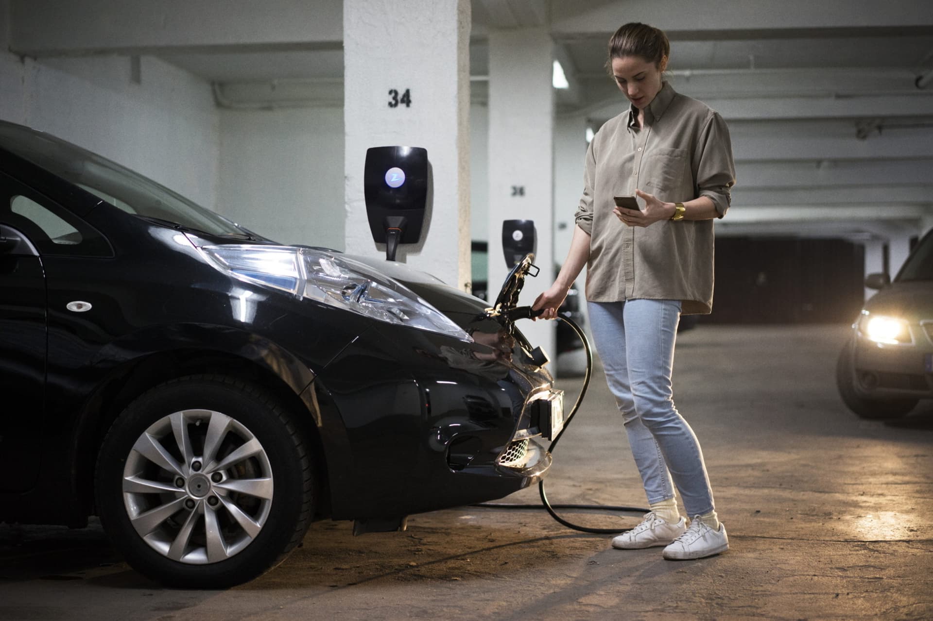 Frau die bei einer Ladestation in der Tiefgarage steht