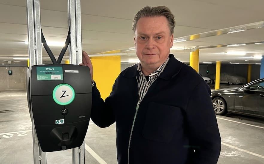 En Zaptec pro laddare installerad i ett parkeringsgarage bredvid laddaren står Stefan från en BRF på smogen