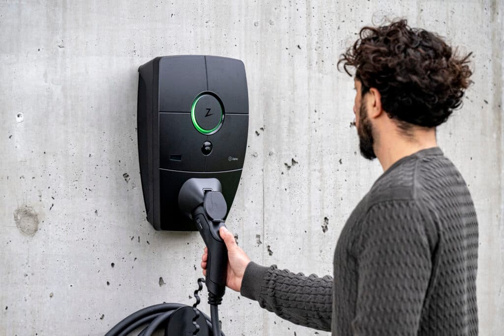 Ein Mann lädt sein E-Auto an einer Wallbox für Zuhause