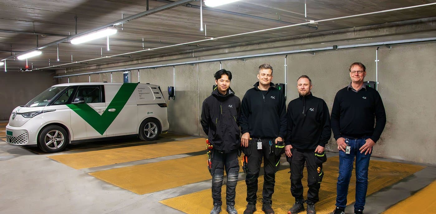 Elektrikere står foran ladeanlegg i en parkeringskjeller.