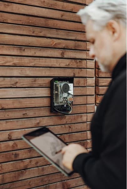 Person med nettbrett foran en åpen Zaptec Go lader montert på en trevegg.