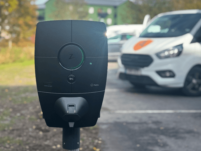 Zaptec Pro o laddbox sitter monterad på en laddstolpe utomhus, i bakgrunden står en vit skåpbil.