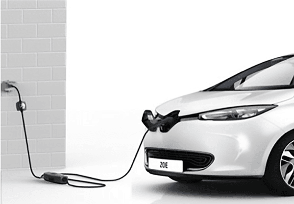 En hvit elbil er koblet til en stikkontakt ved hjelp av en bærbar lader. Kabelen går fra kontakten til bilens front – en enkel hjemmeladingsløsning.