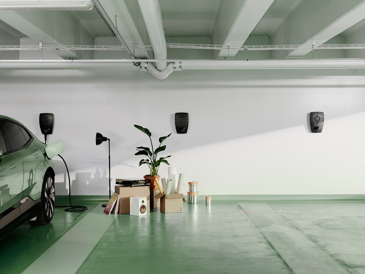 Grønn bil lader med Zaptec Pro lader på hvit vegg i parkeringshus, flyttescene med esker, lampe, plante og høyttaler på grønt gulv.