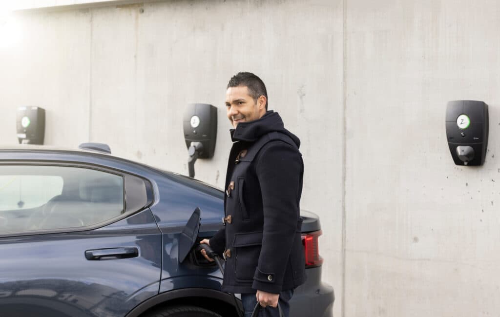 Ein Mann lädt sein Elektroauto an einer Wallbox auf.