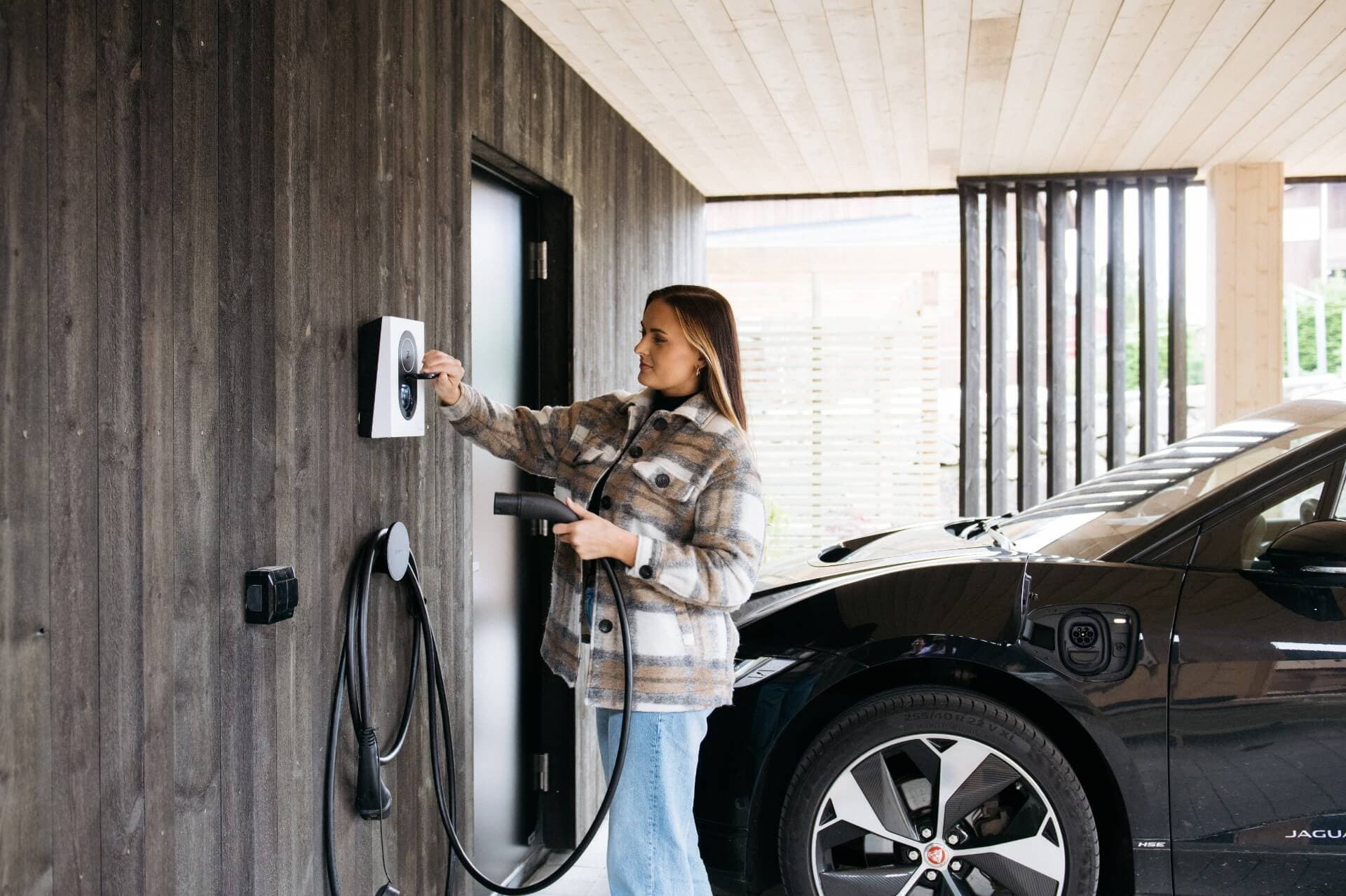 Eine Frau lädt Zuhause ihren Firmenwagen