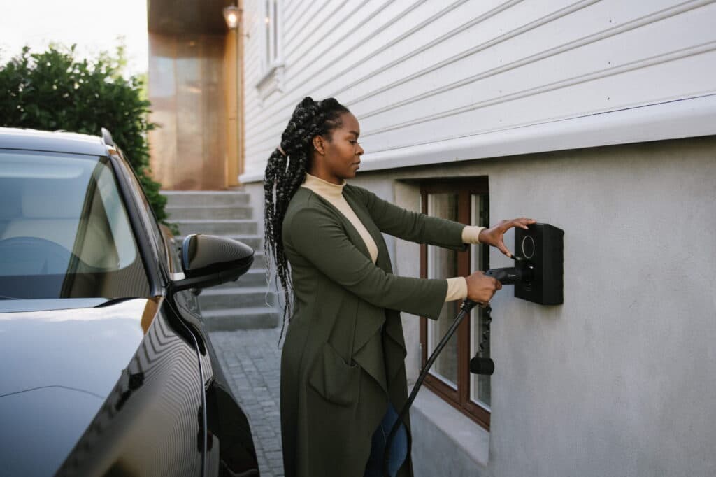 Eine Frau schließt ein Ladekabel an einer geförderten Wallbox an