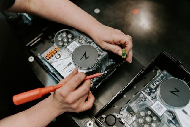 En person monterer de interne komponentene i en Zaptec-lader. Med verktøy i hånden jobber de presist