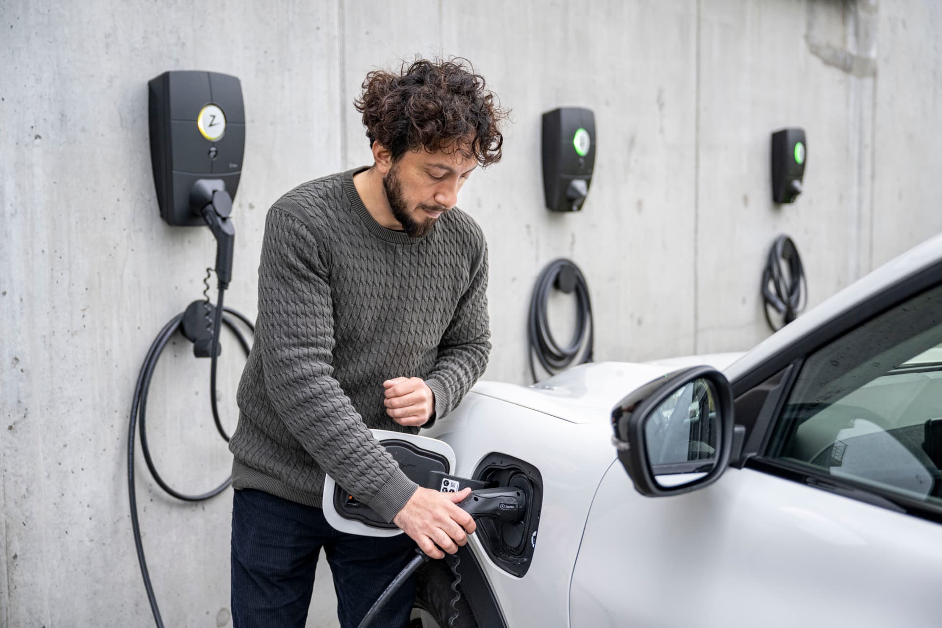 Ein Mann lädt sein Elektroauto an einer Ladestation in einem Parkhaus