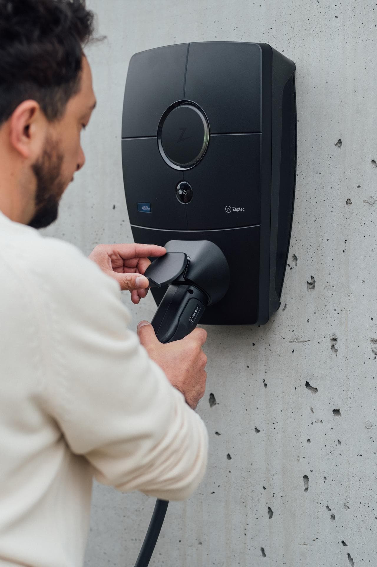Ein Mann schließt ein Ladekabel an einer Wallbox auf dem Unternehmensstandort an