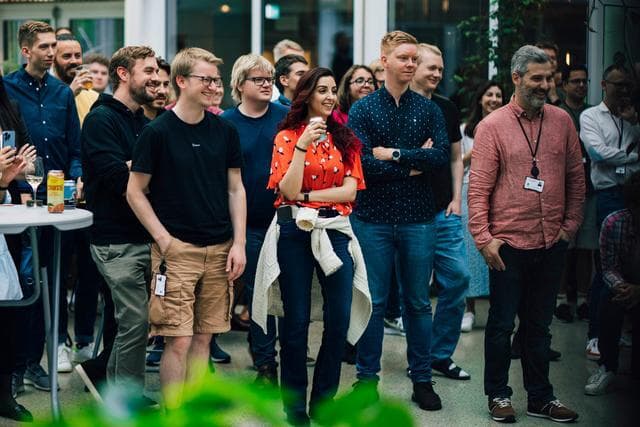 En grupp av människor står och kollar år samma håll, de ser glada och engagerade ut.