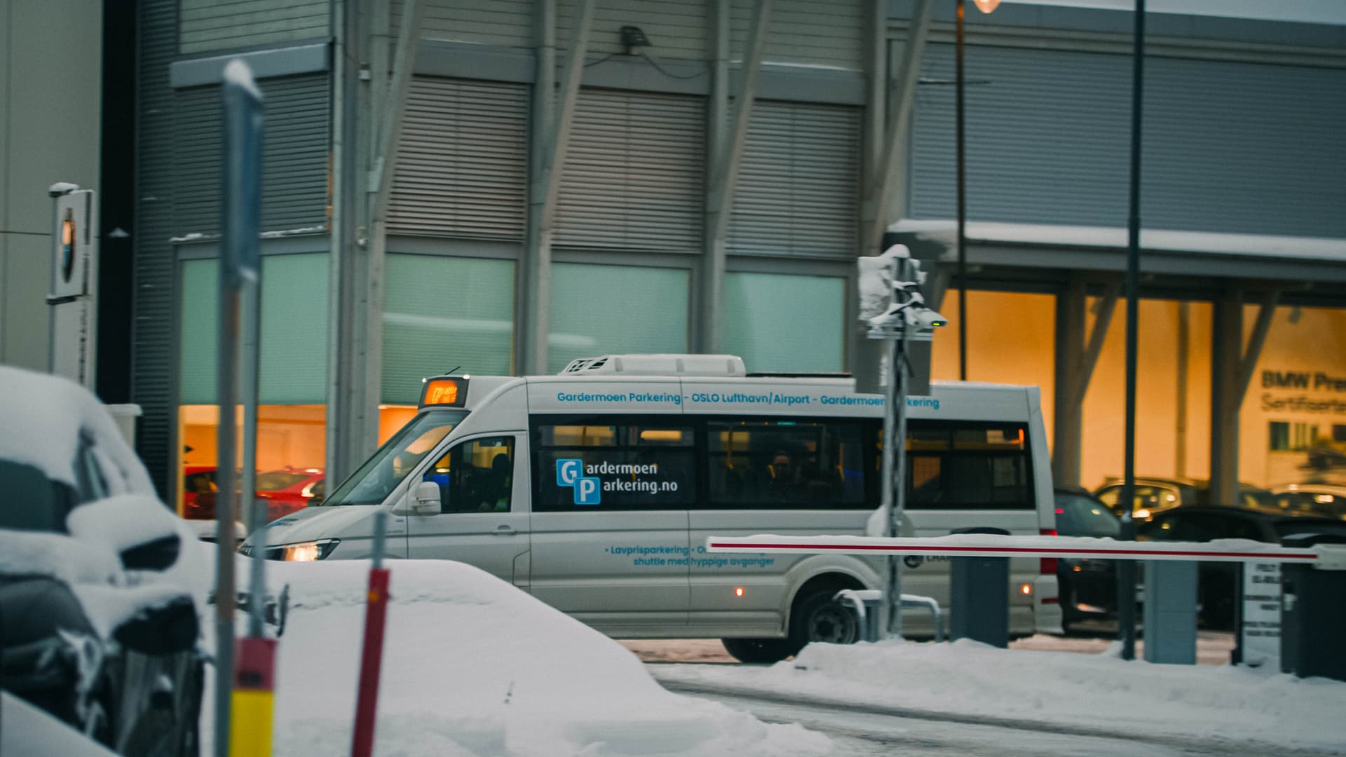 en snötäckt parkering framför en glasfasad, en minibuss i silver åker förbi