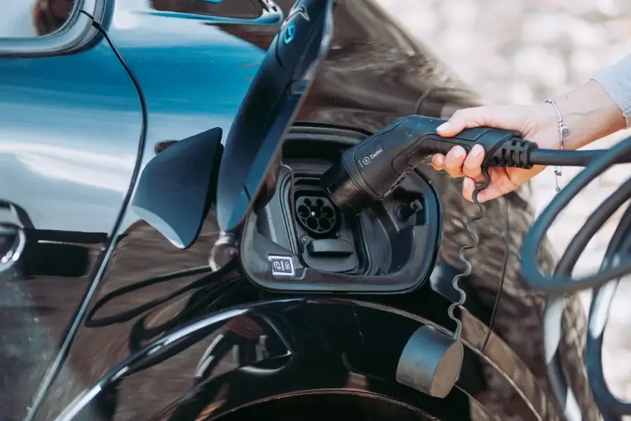 Person som ansluter en Zaptec laddkabel till en svart elbil.